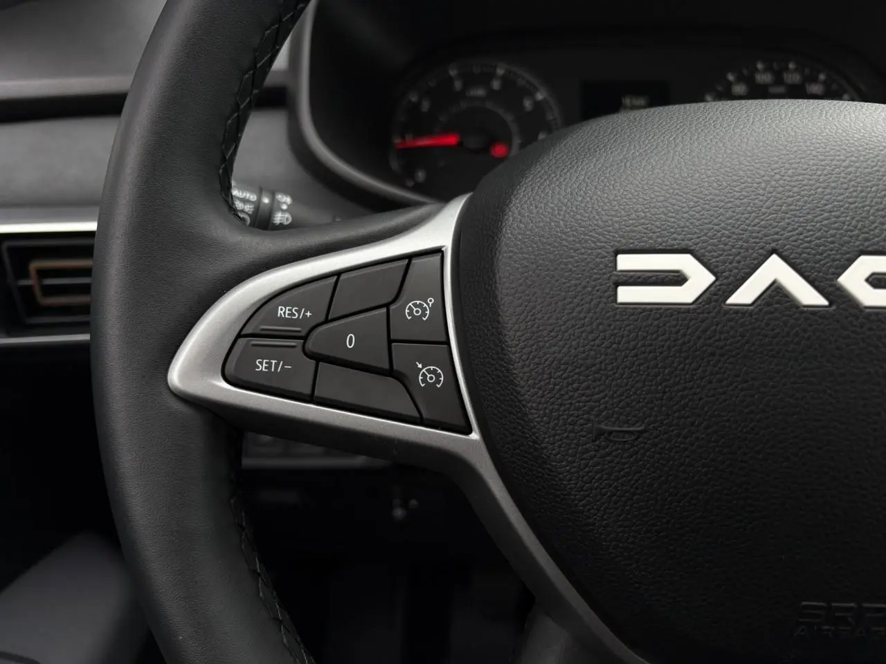 Gros plan sur le volant noir de la Dacia Sandero Stepway 2025 avec commandes de régulateur de vitesse intégrées.