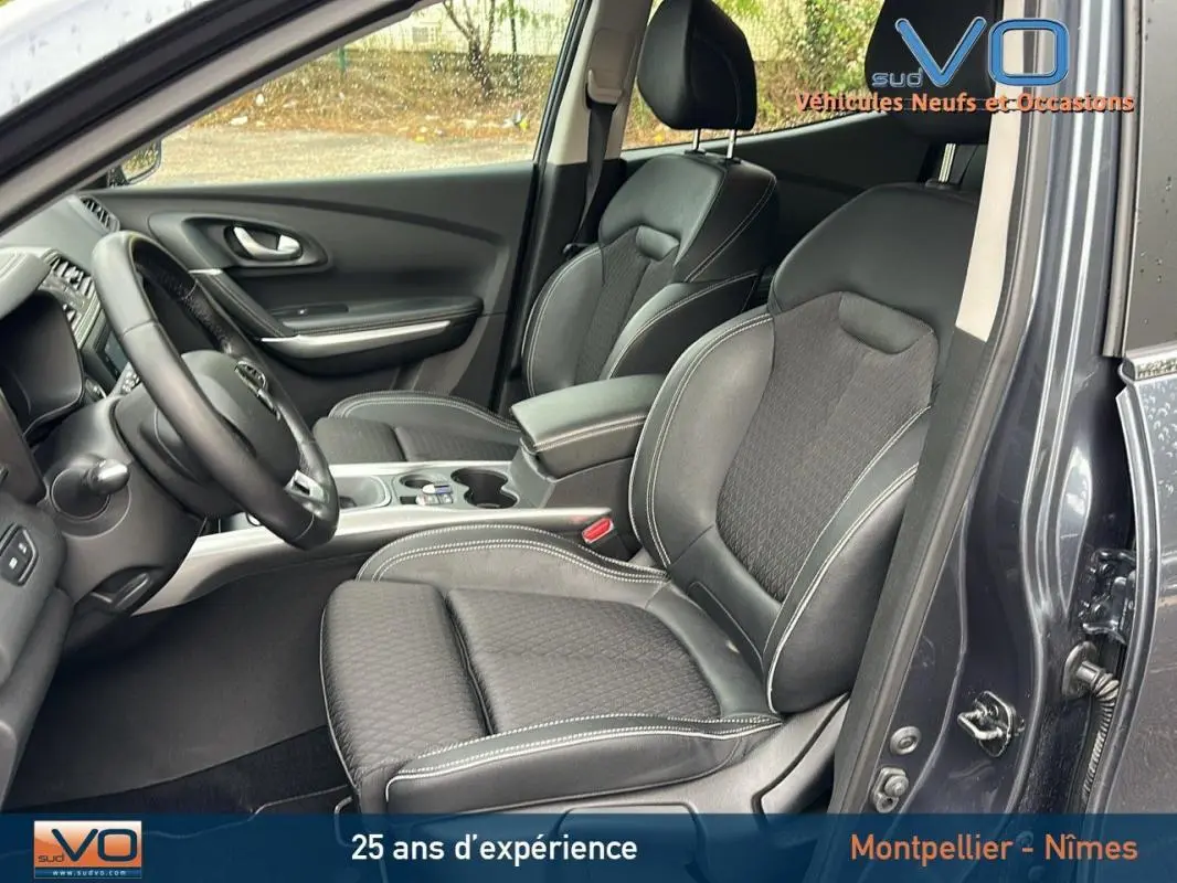 Vue intérieure côté conducteur du Renault Kadjar gris 2019, sièges cuir noirs avec surpiqûres blanches et console centrale.