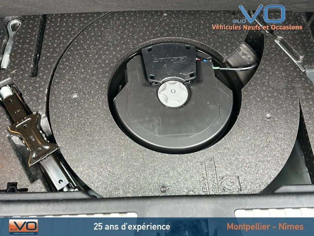 Vue rapprochée du compartiment de rangement sous le coffre du Renault Kadjar gris, montrant la roue de secours et les outils.