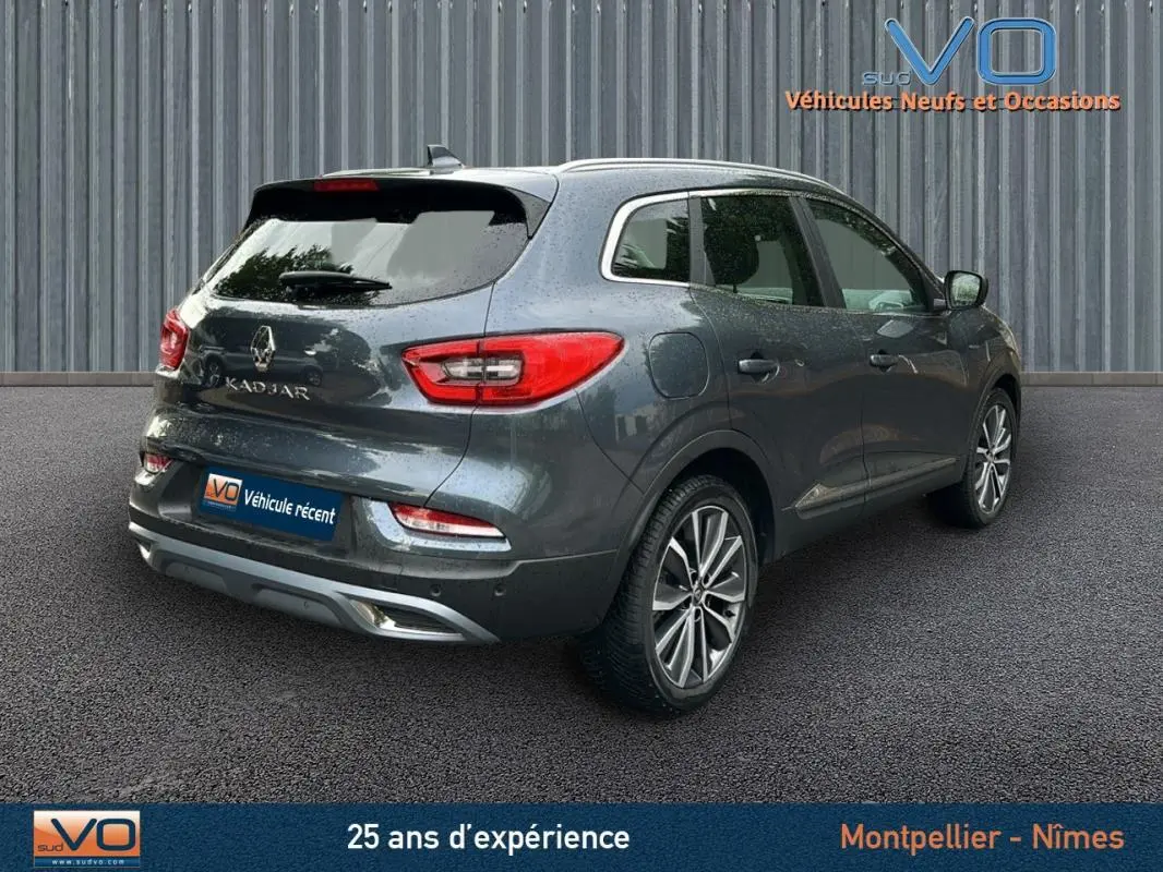 Vue 3/4 arrière droite d'un Renault Kadjar gris 2019 avec jantes alliage 18 pouces et barres de toit visibles