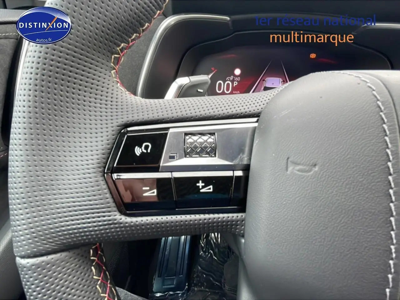 Gros plan sur le volant cuir perforé côté gauche du DS7 noir avec commandes intégrées et palettes au volant.