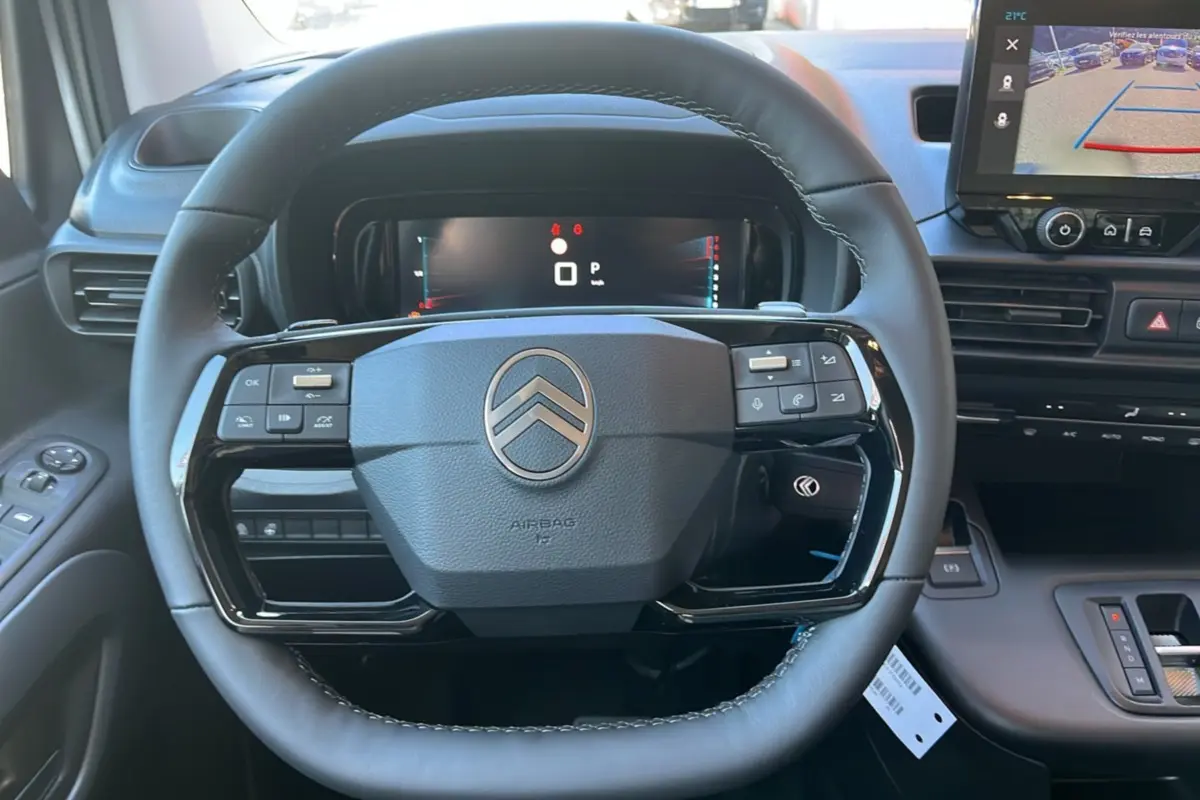 Vue rapprochée du volant cuir multifonctions du Citroën Berlingo 2025 avec tableau de bord digital et écran tactile.