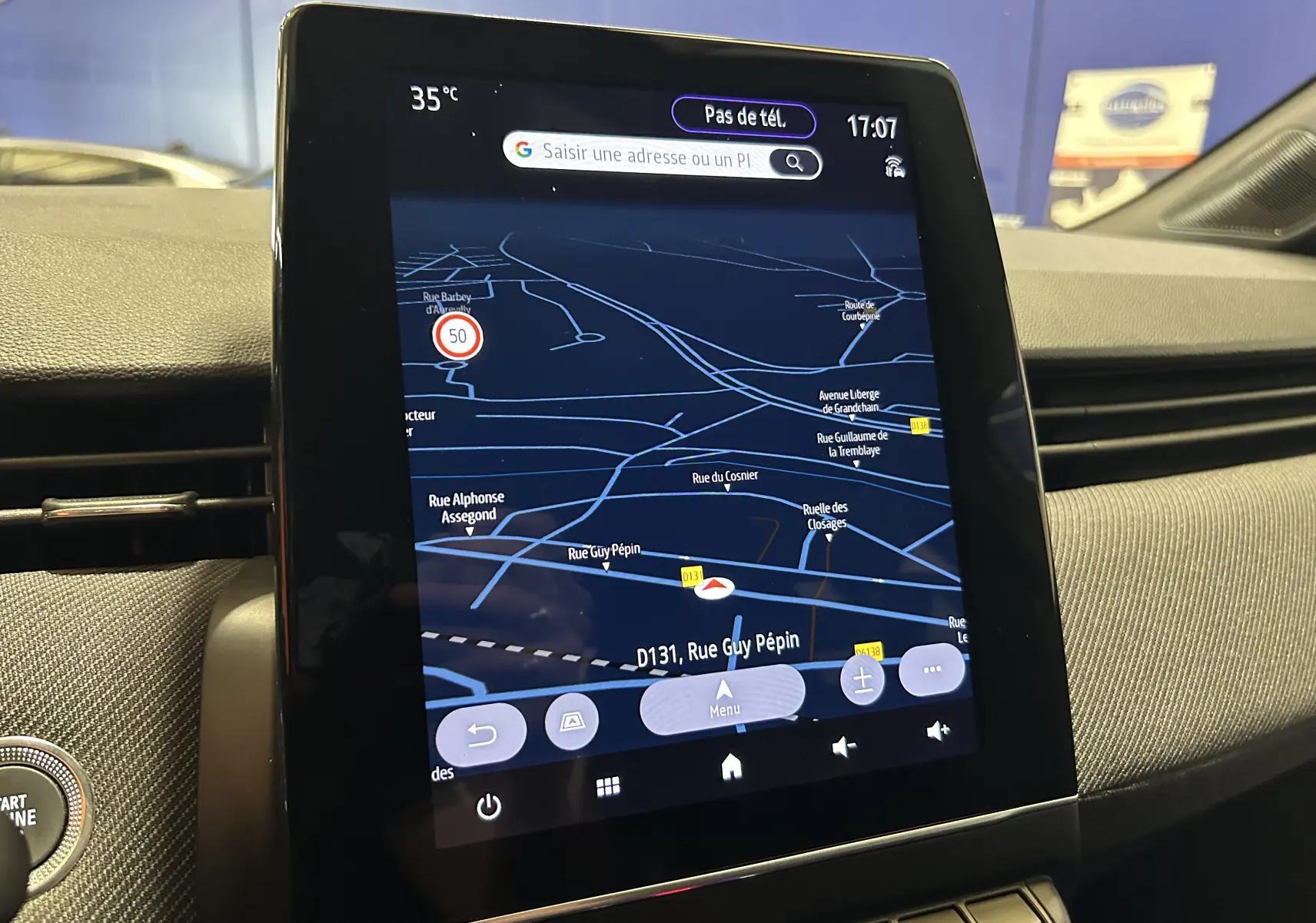 Vue rapprochée de l’écran tactile central du GPS dans une Renault Clio V gris schiste, affichant une carte de navigation nocturne.