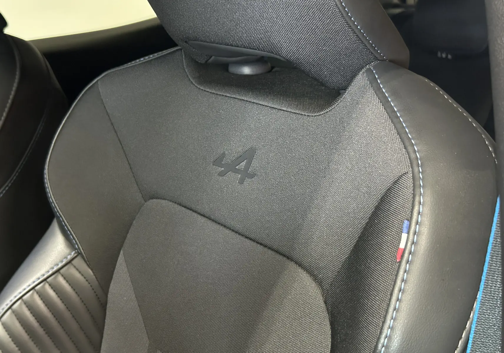 Gros plan sur le siège avant noir de la Renault Clio V TCe 90 Esprit Alpine avec logo Alpine et surpiqûres bleues.