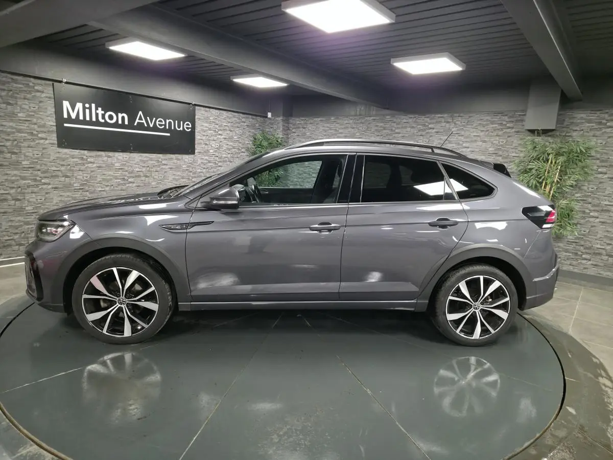 Volkswagen Taigo gris foncé vue de profil côté gauche, avec jantes alliage noires et toit noir.