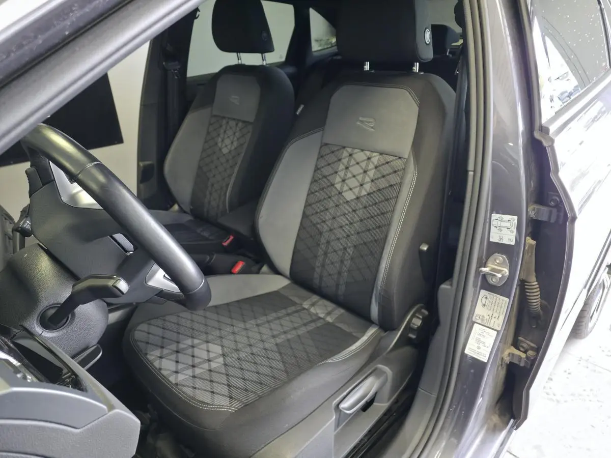 Vue intérieure côté conducteur du Volkswagen Taigo gris foncé, sièges sport R-Line en tissu avec motifs géométriques.