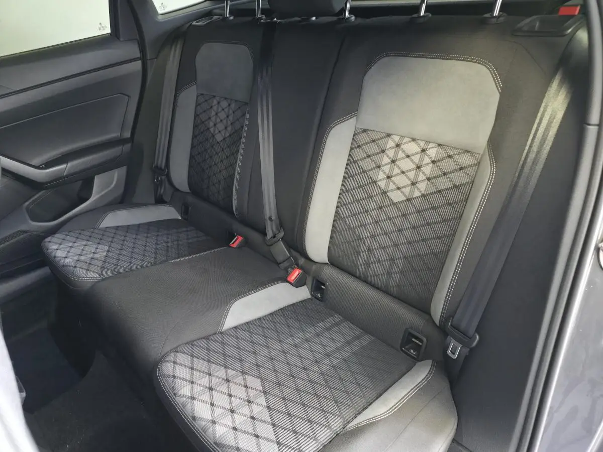 Vue intérieure côté arrière droit montrant la banquette arrière gris foncé avec motifs géométriques et ceintures de sécurité.