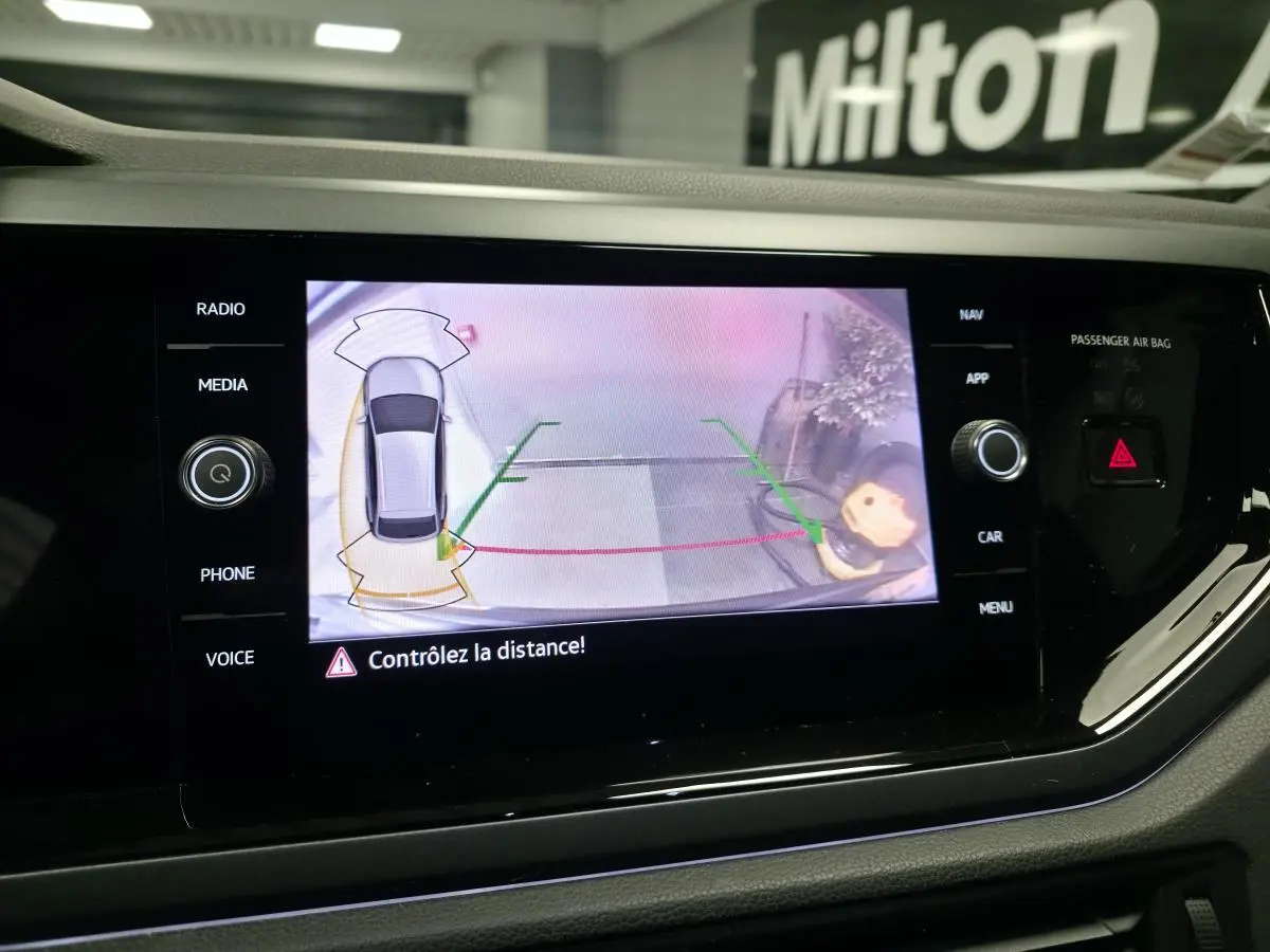 Écran tactile intérieur affichant la caméra de recul du Volkswagen Taigo gris foncé avec aides au stationnement activées.