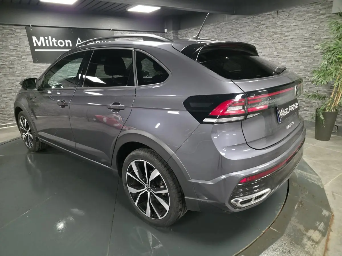 Volkswagen Taigo gris foncé en 3/4 arrière droit, avec jantes alliage noires et feux arrière LED distinctifs.