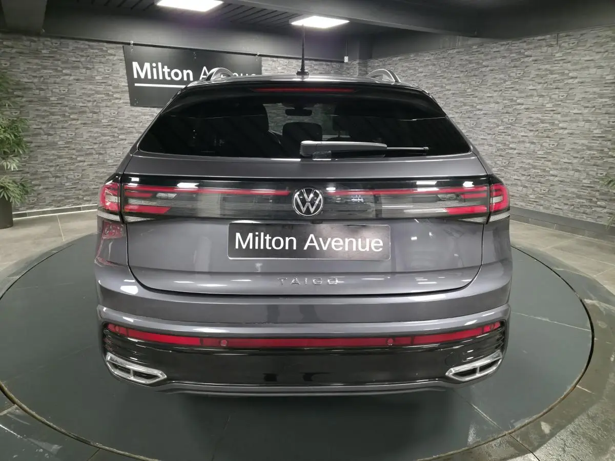 Vue arrière d'un Volkswagen Taigo gris foncé avec feux LED reliés par une baguette lumineuse et double sorties d'échappement chromées.