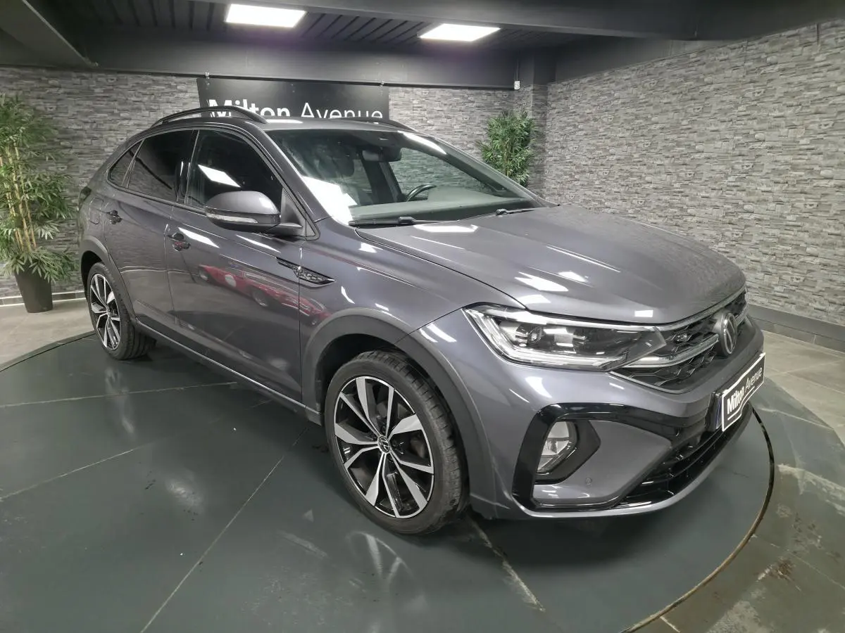 Volkswagen Taigo gris foncé en 3/4 avant droit avec jantes alliage noires et détails R-Line visibles.