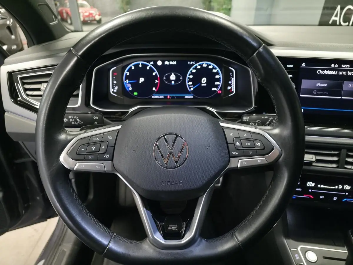 Vue rapprochée du volant cuir noir multifonctions et du tableau de bord numérique du Volkswagen Taigo gris foncé R-Line.