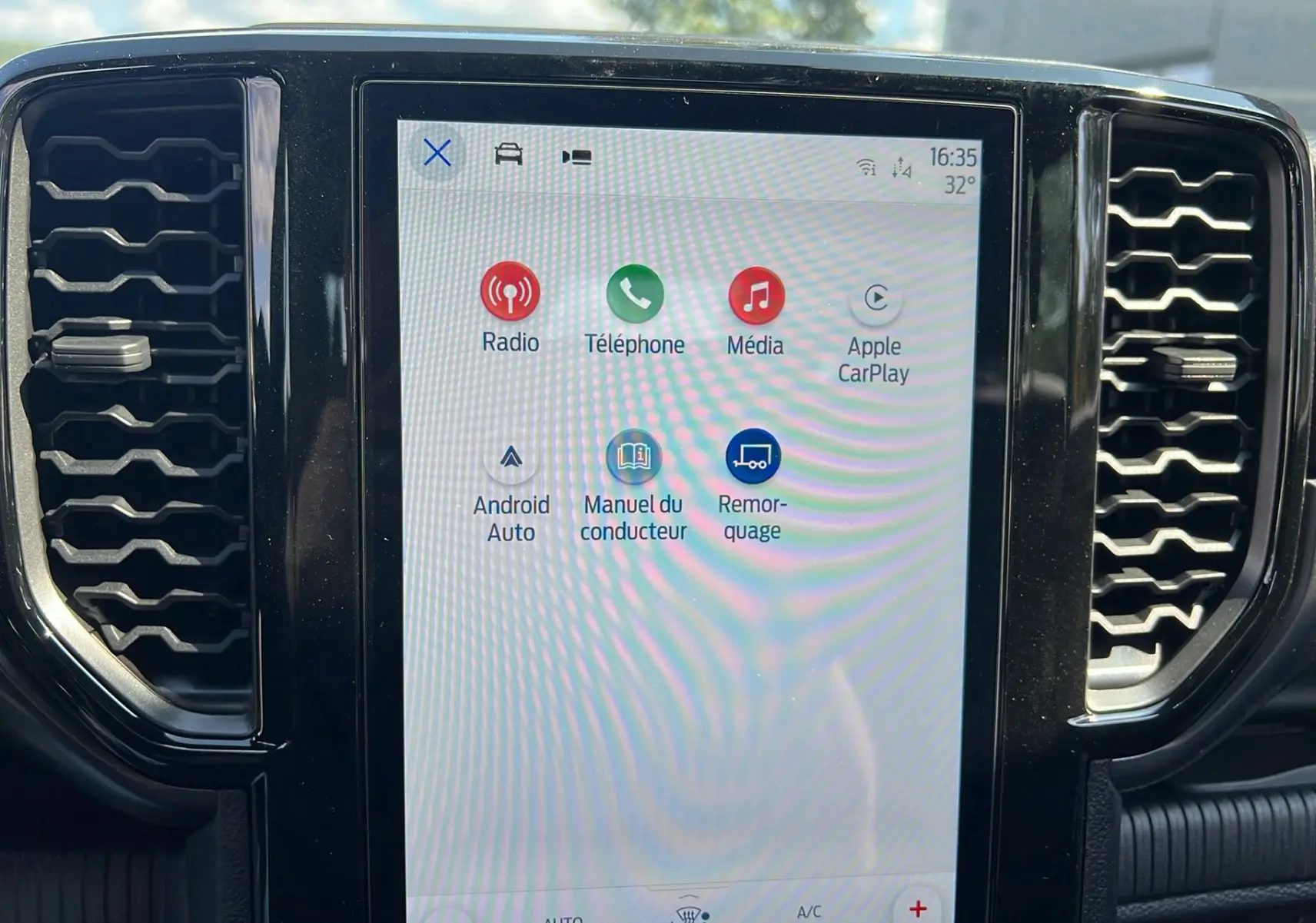 Écran tactile central du Ford Ranger 2025 affichant les options multimédia et connectivité dans un intérieur noir.