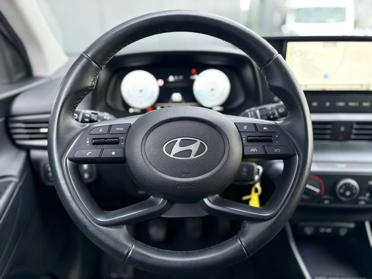 Vue rapprochée du volant cuir noir de la Hyundai i20 2025 avec commandes intégrées et tableau de bord numérique.