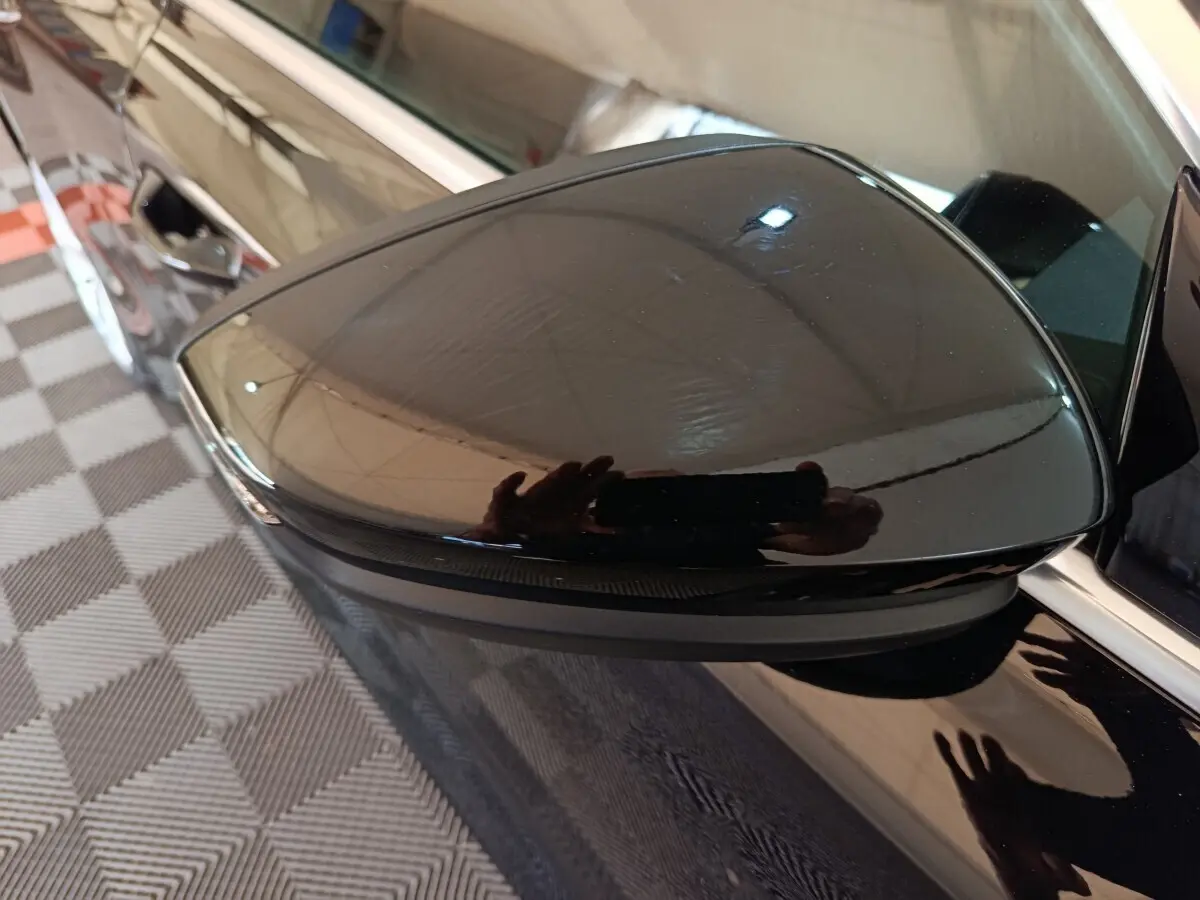 Rétroviseur côté gauche noir brillant de l'Audi A3 35 TDI 150 S tronic Business Line 2023, reflet net sur carrosserie noire.