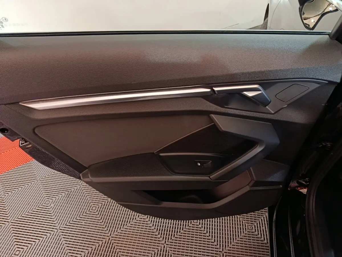 Vue intérieure côté gauche de la porte noire d'une Audi A3 35 TDI 150 S tronic Business Line avec poignée argentée.