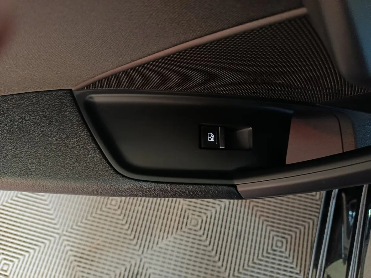 Gros plan sur le bouton de commande de la vitre côté gauche de la porte intérieure noire d’une Audi A3 35 TDI 2023.