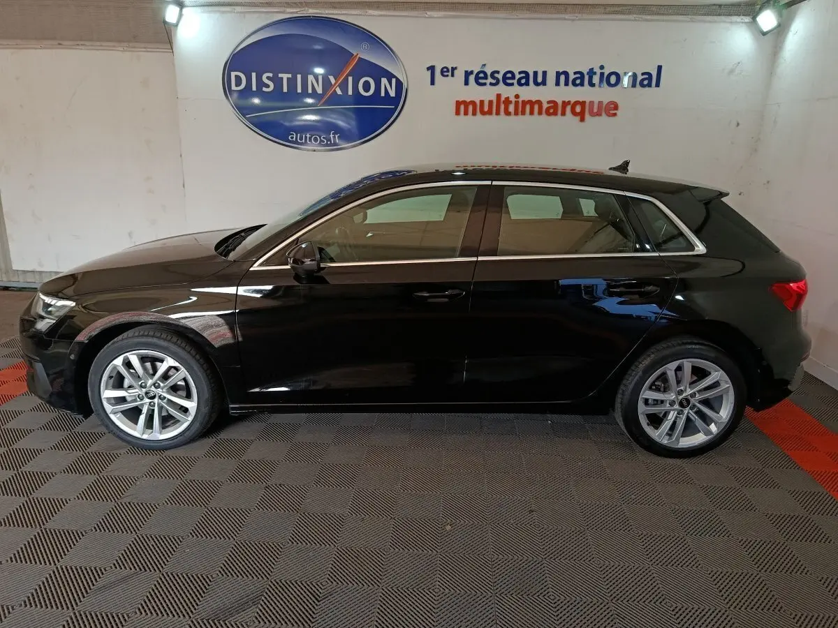 Audi A3 35 TDI Business Line noire vue de profil côté gauche dans un showroom avec logo Distinxion en arrière-plan.