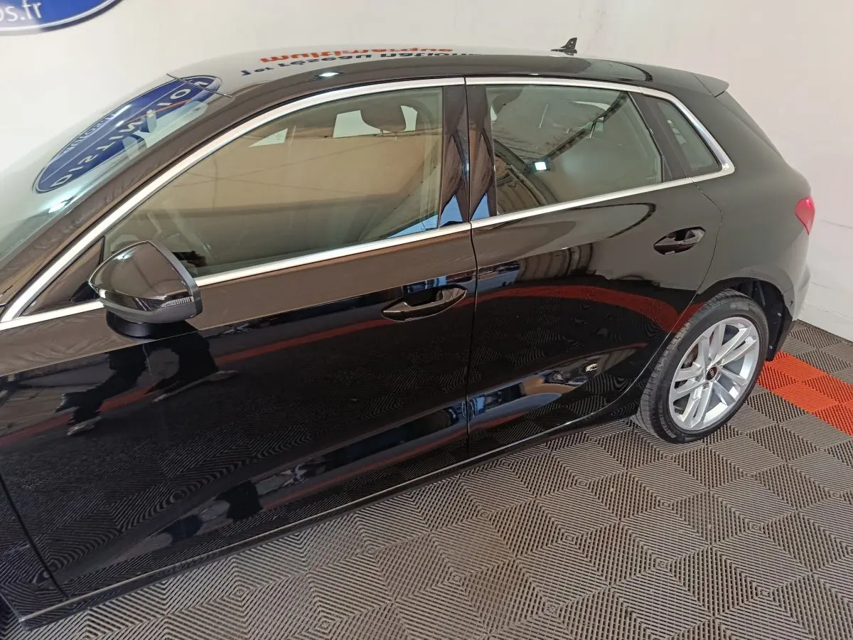 Vue latérale côté gauche d'une Audi A3 noire 2023 avec jantes alliage et rétroviseur noir brillant.