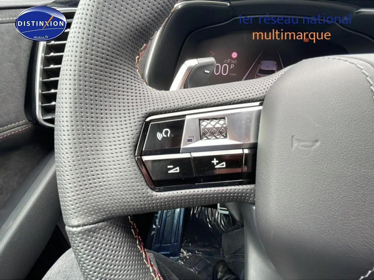 Gros plan sur le volant cuir perforé gris du DS7 1.5 BlueHDi 130, avec commandes intégrées et tableau de bord numérique visible.
