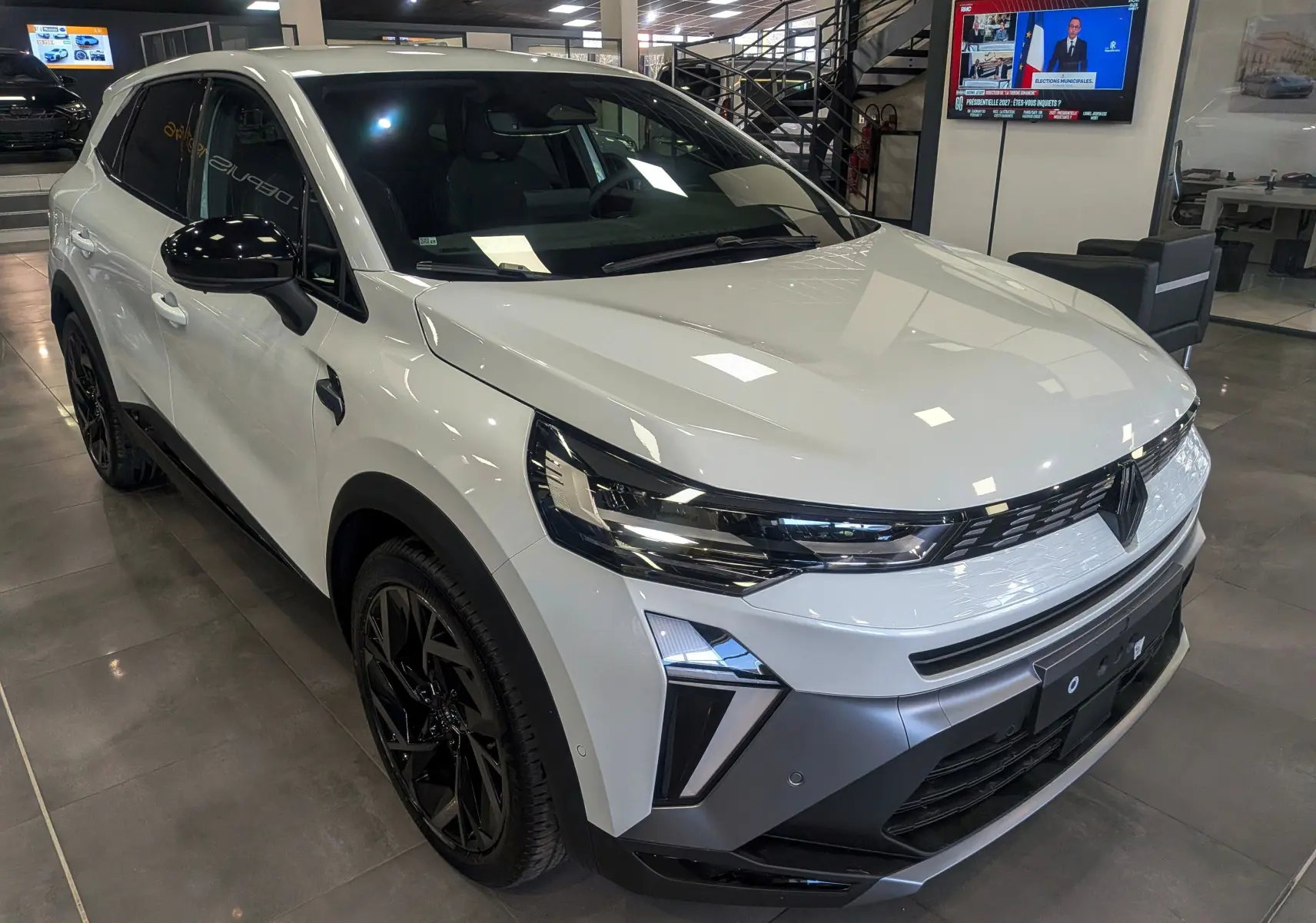 Renault SYMBIOZ blanc nacré en 3/4 avant droit, avec jantes noires et détails noirs contrastants sur les rétroviseurs.