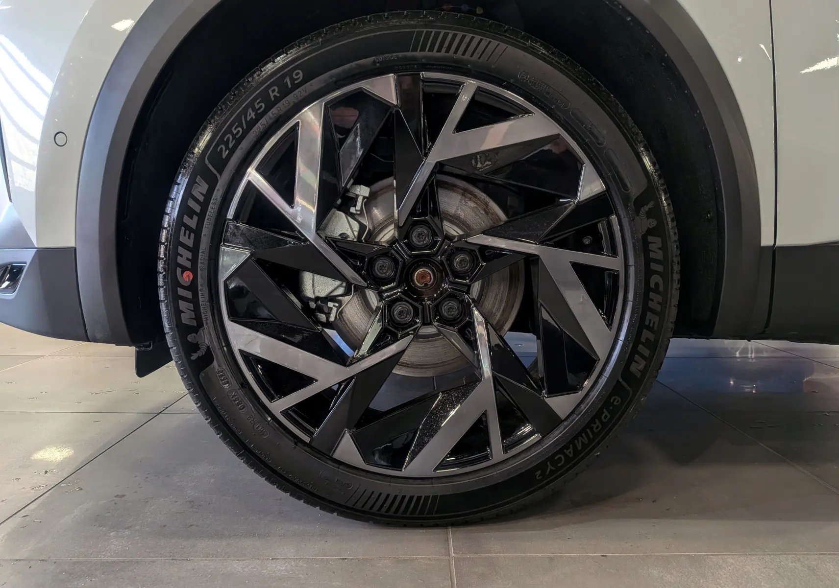 Gros plan sur la roue avant droite du Renault SYMBIOZ blanc nacré, avec jante noire et argentée au design géométrique.