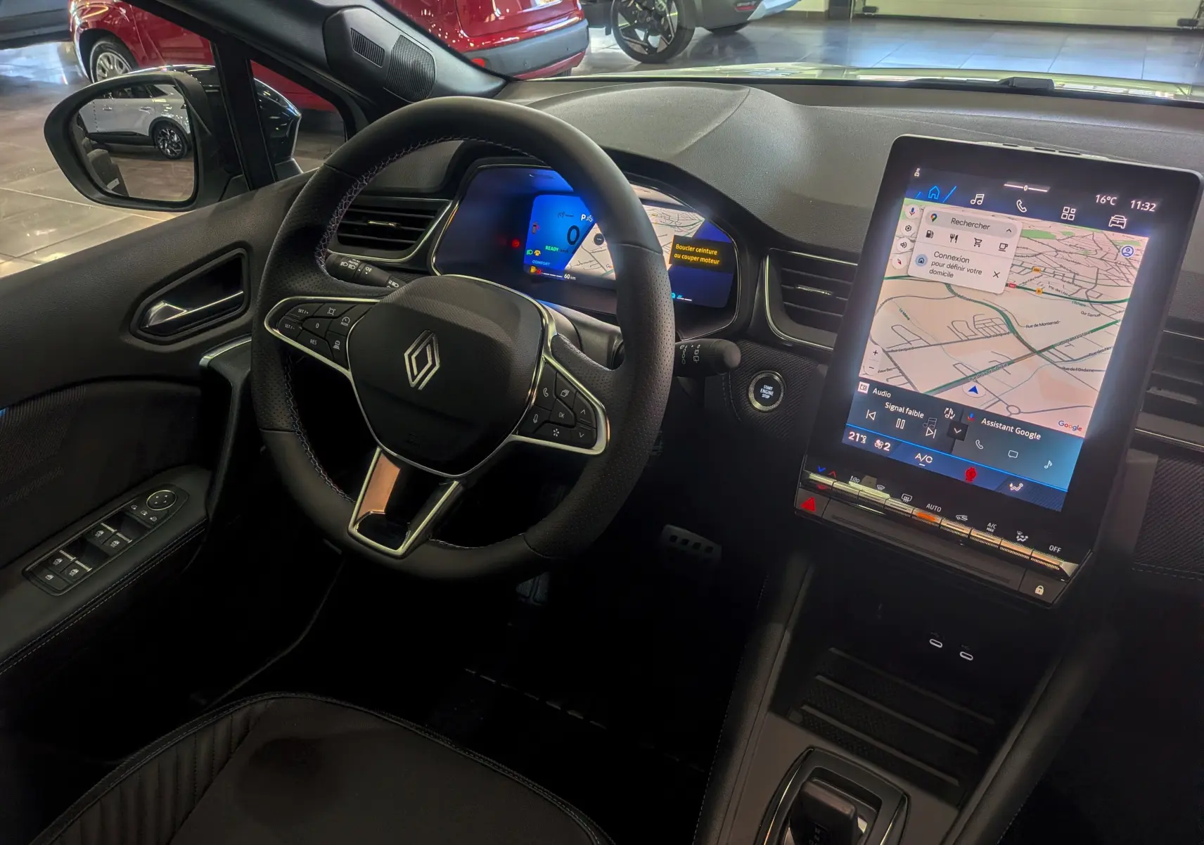Vue intérieure côté conducteur du Renault SYMBIOZ E-TECH avec volant multifonction et grand écran tactile vertical.