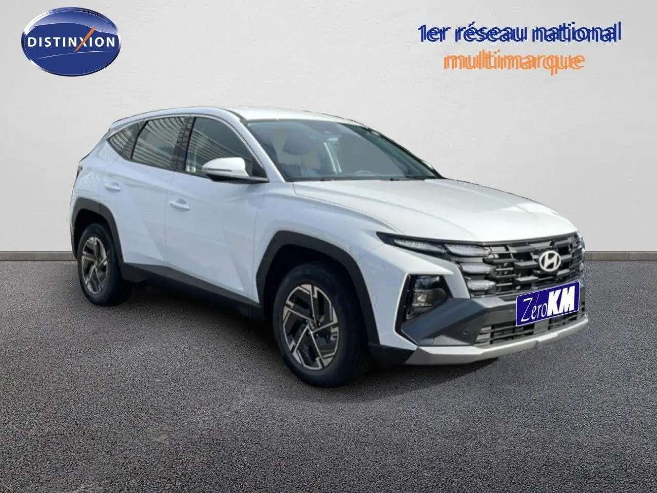 Hyundai Tucson blanc atlas en 3/4 avant droit, avec calandre imposante et jantes alliage bicolores.