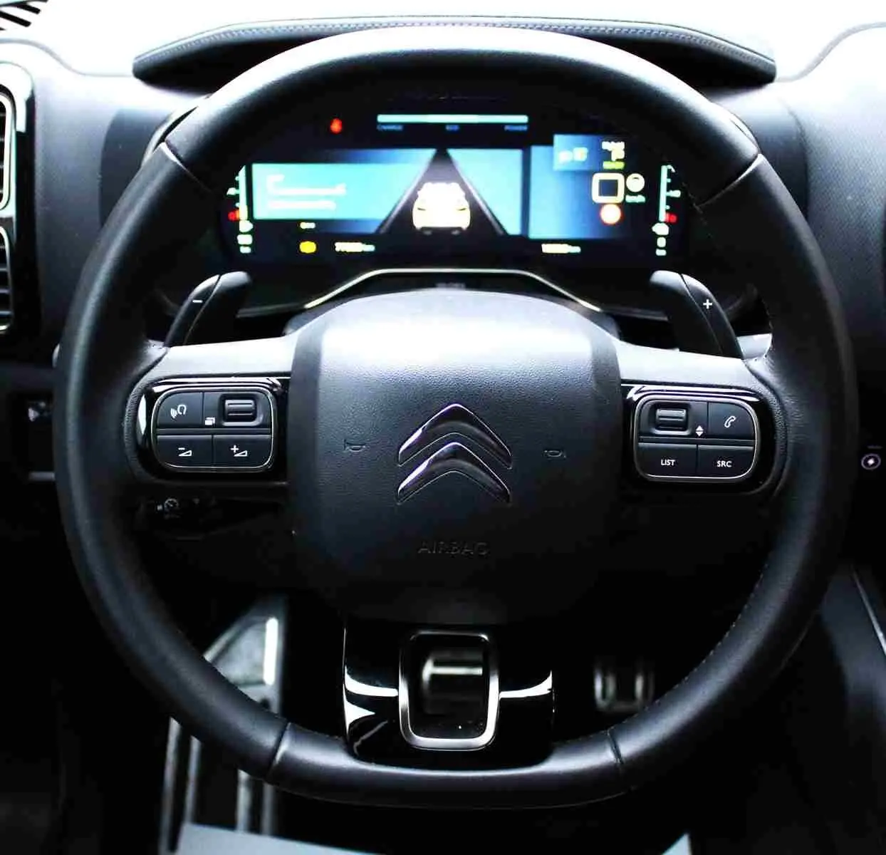 Vue rapprochée du volant noir de la Citroën C5 Aircross hybride rechargeable avec tableau de bord numérique lumineux.