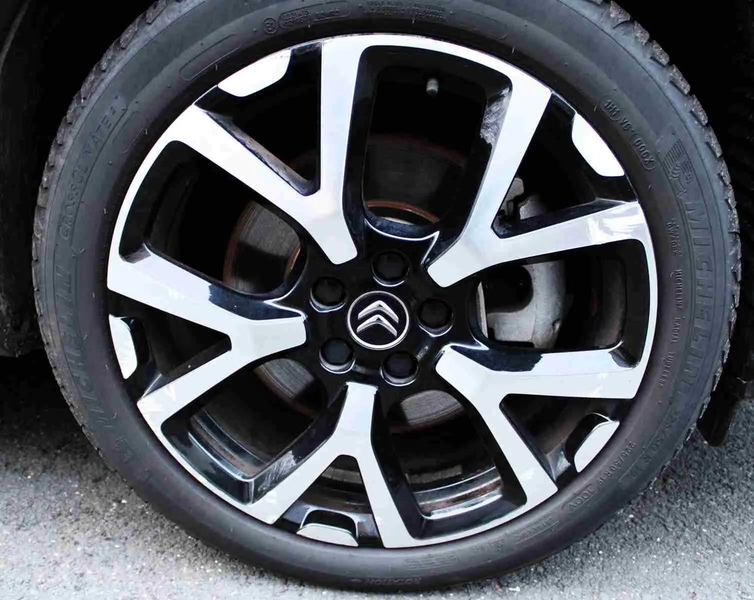Gros plan sur la jante alliage bicolore noire et argent avec logo Citroën au centre, roue du C5 Aircross gris platinium.