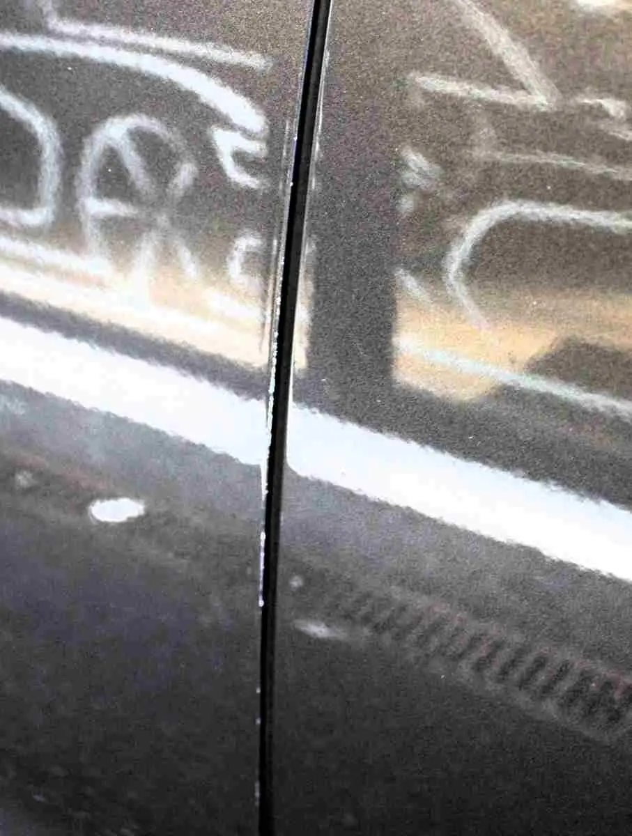 Gros plan sur la jonction entre deux panneaux latéraux du Citroën C5 Aircross gris platinium, reflet flou d’un autre véhicule visible.