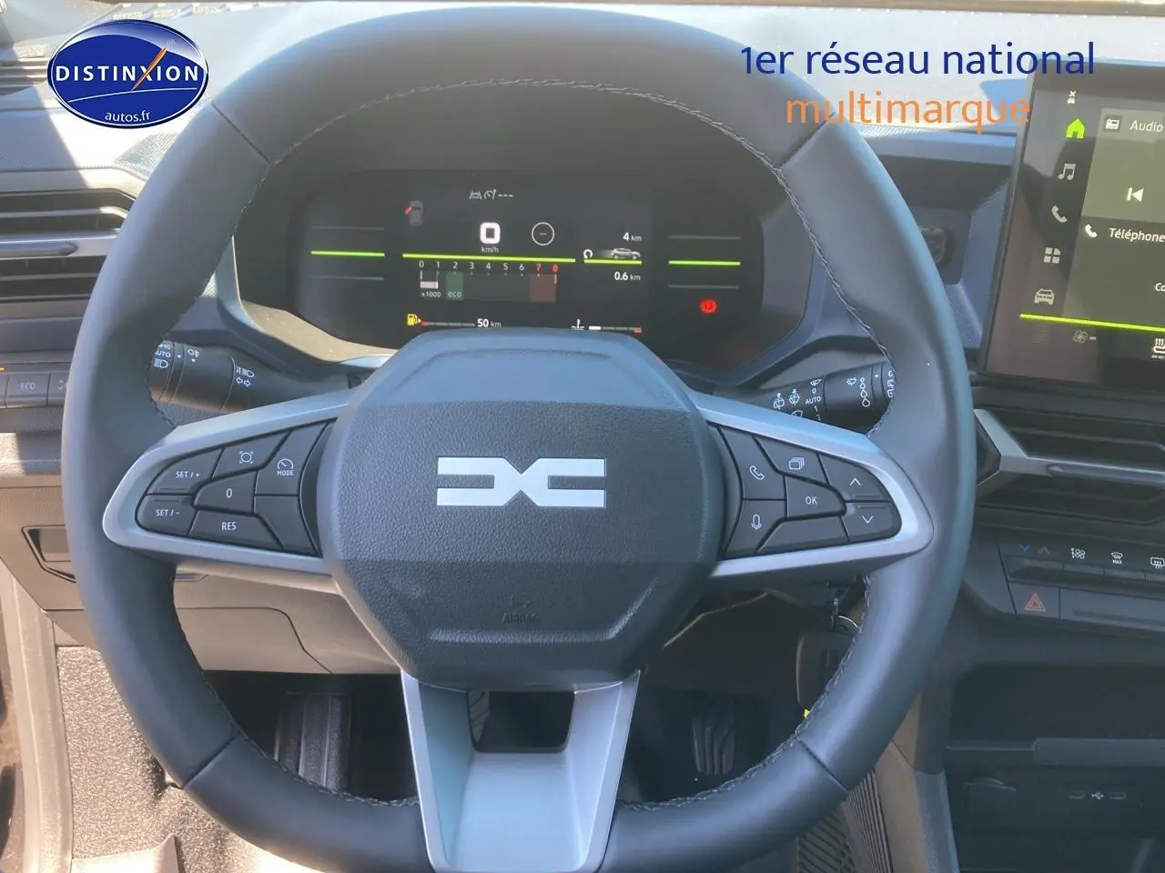 Vue rapprochée du volant multifonction noir et gris du Dacia Duster 2025 avec tableau de bord numérique et écran tactile.