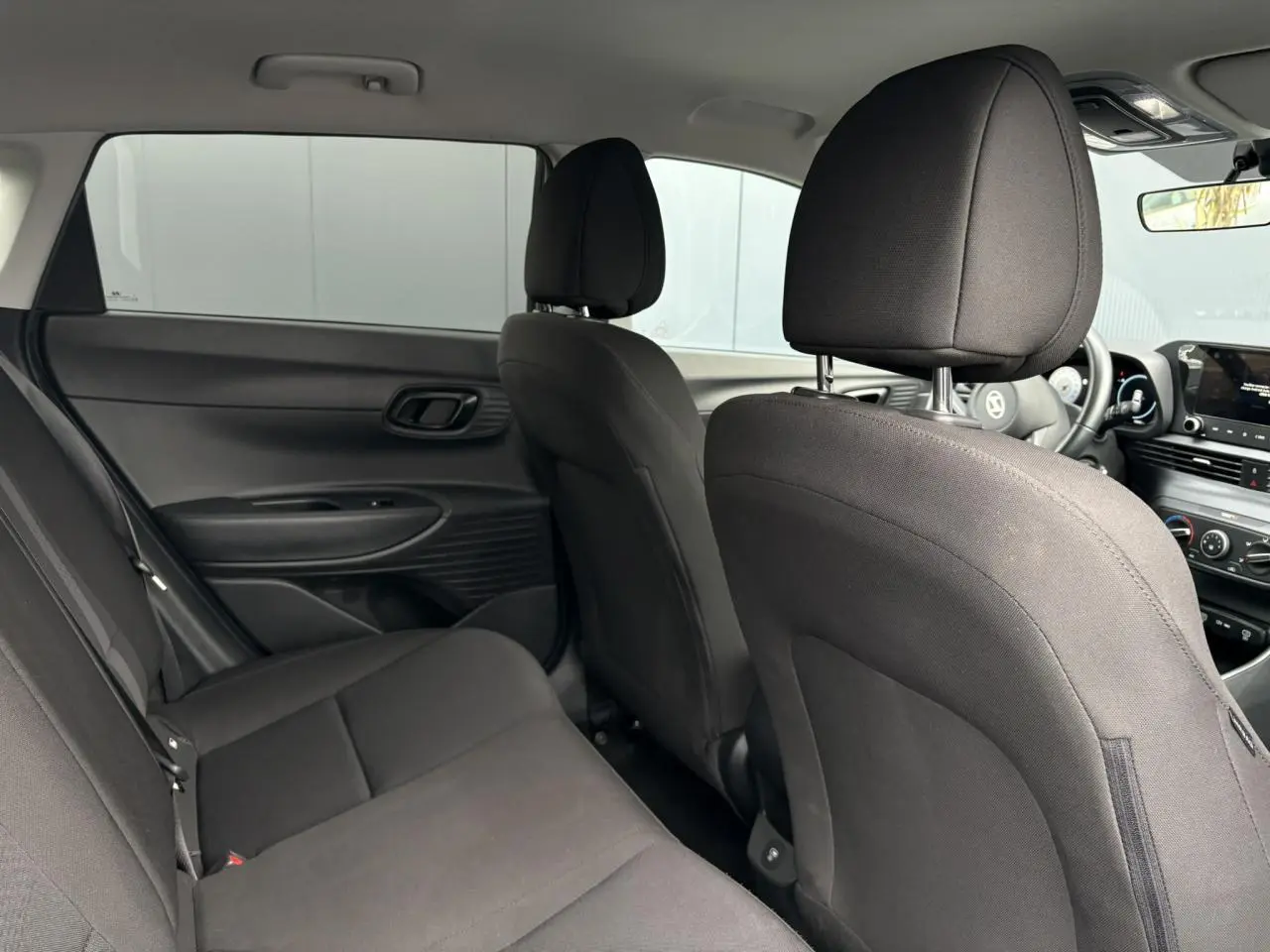 Vue intérieure arrière de la Hyundai i20 2025 avec sièges tissu noirs et tableau de bord visible côté droit.