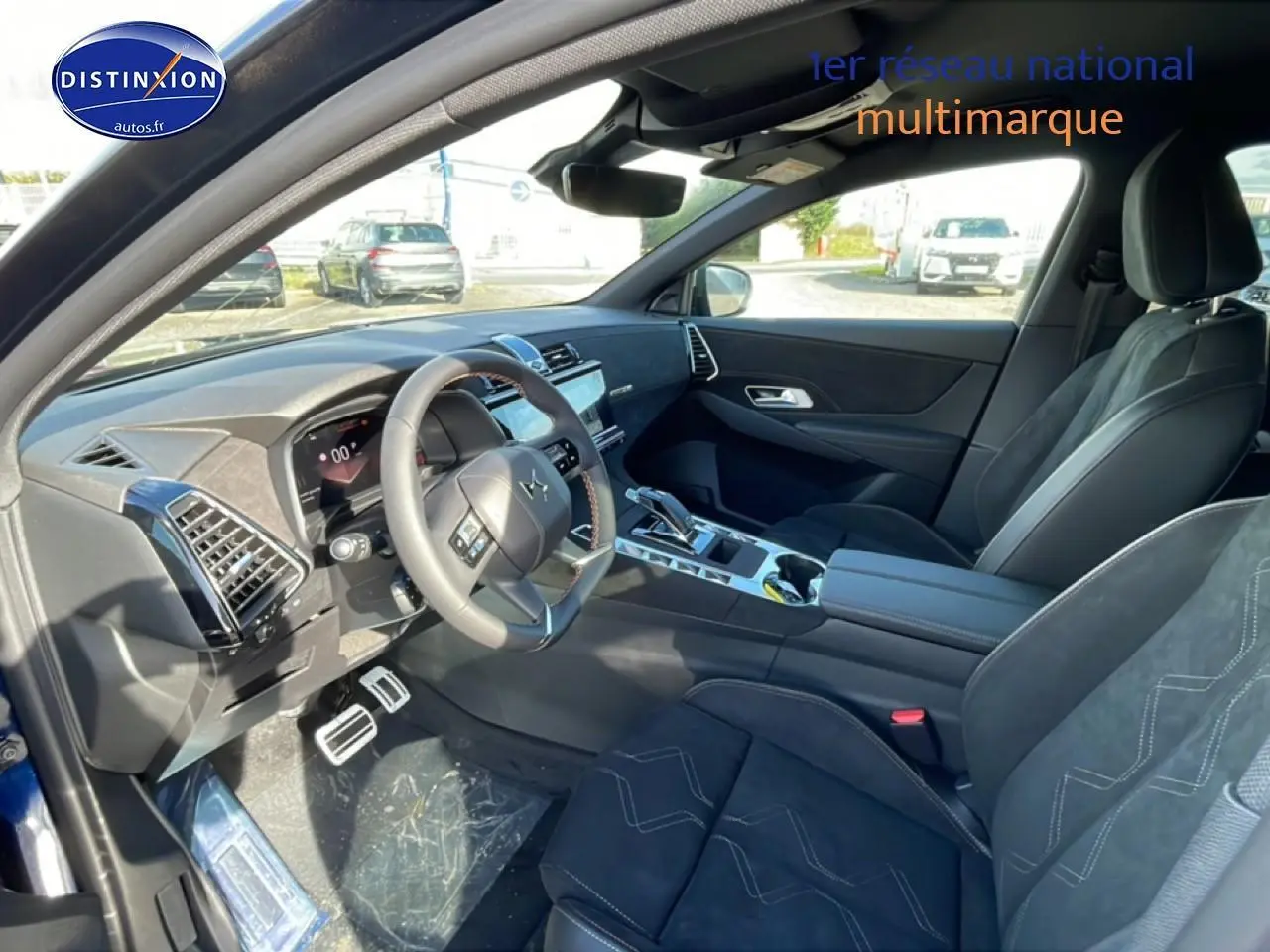 Vue intérieure côté conducteur du DS7 bleu 2026, mettant en valeur le volant cuir, la console centrale et les sièges noirs.