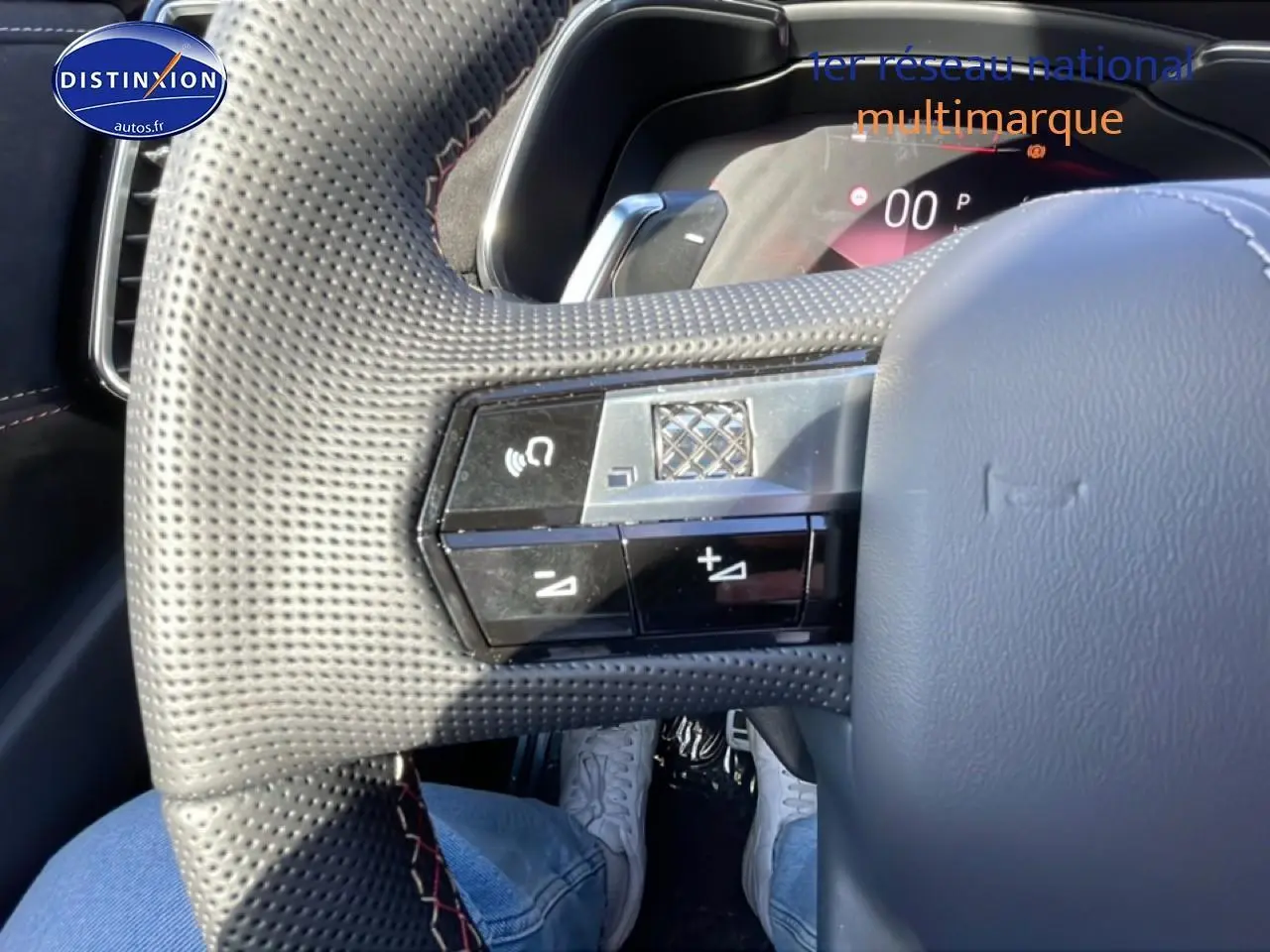 Gros plan sur le volant cuir perforé du DS7 bleu 1.5 BlueHDi 130, avec commandes intégrées et coutures rouges visibles.