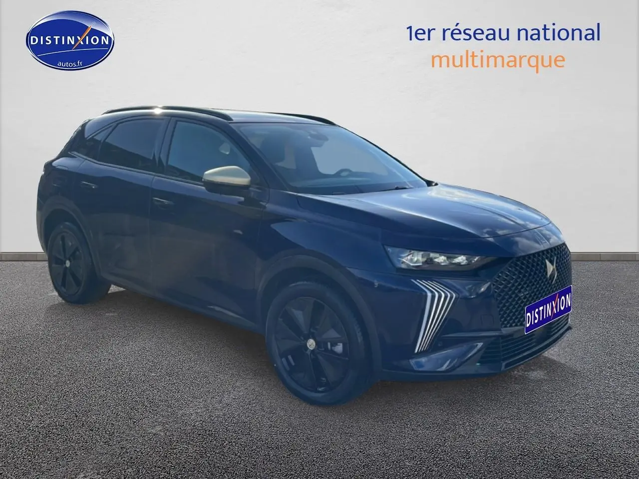DS7 bleu 3/4 avant droit avec calandre distinctive et jantes noires sur fond neutre.