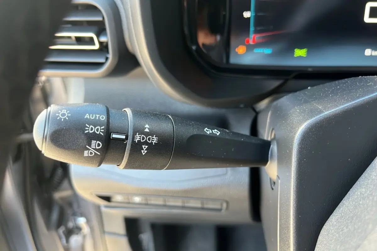 Gros plan sur la commande des feux et clignotants du Citroën Berlingo 2025, intérieur noir avec écran digital.