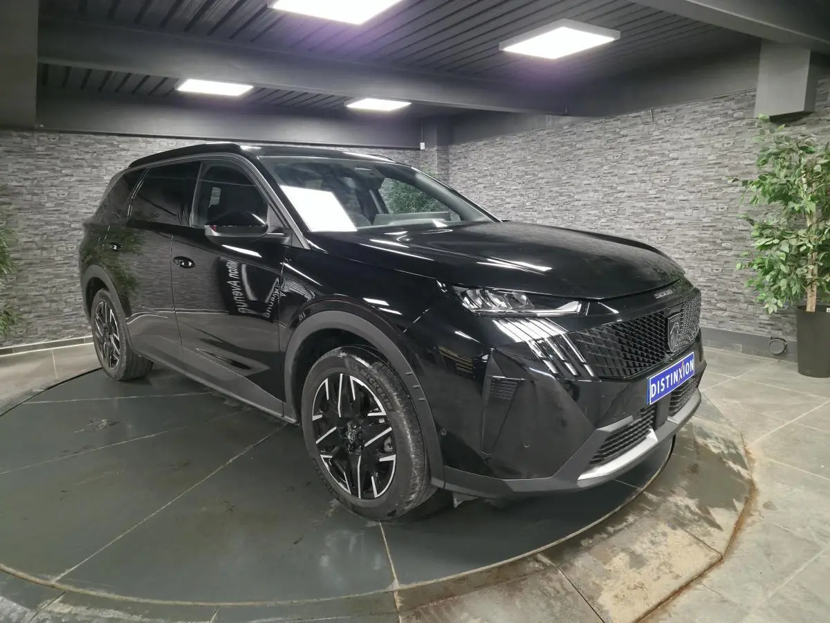 Peugeot 5008 noir vue 3/4 avant droit en intérieur, avec jantes alliage 19'' et calandre noire distinctive.