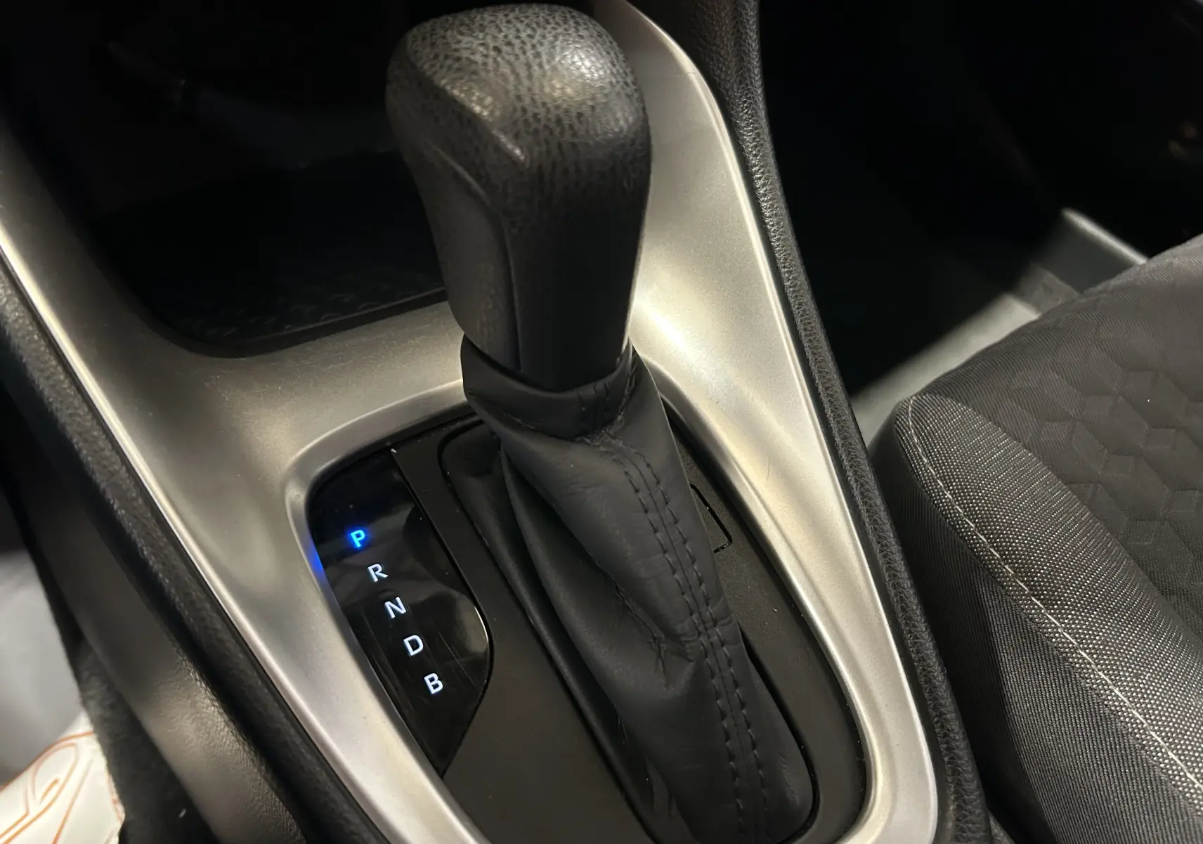 Le levier de vitesse automatique noir de la Toyota Yaris 116h, avec indication des modes éclairés en bleu.