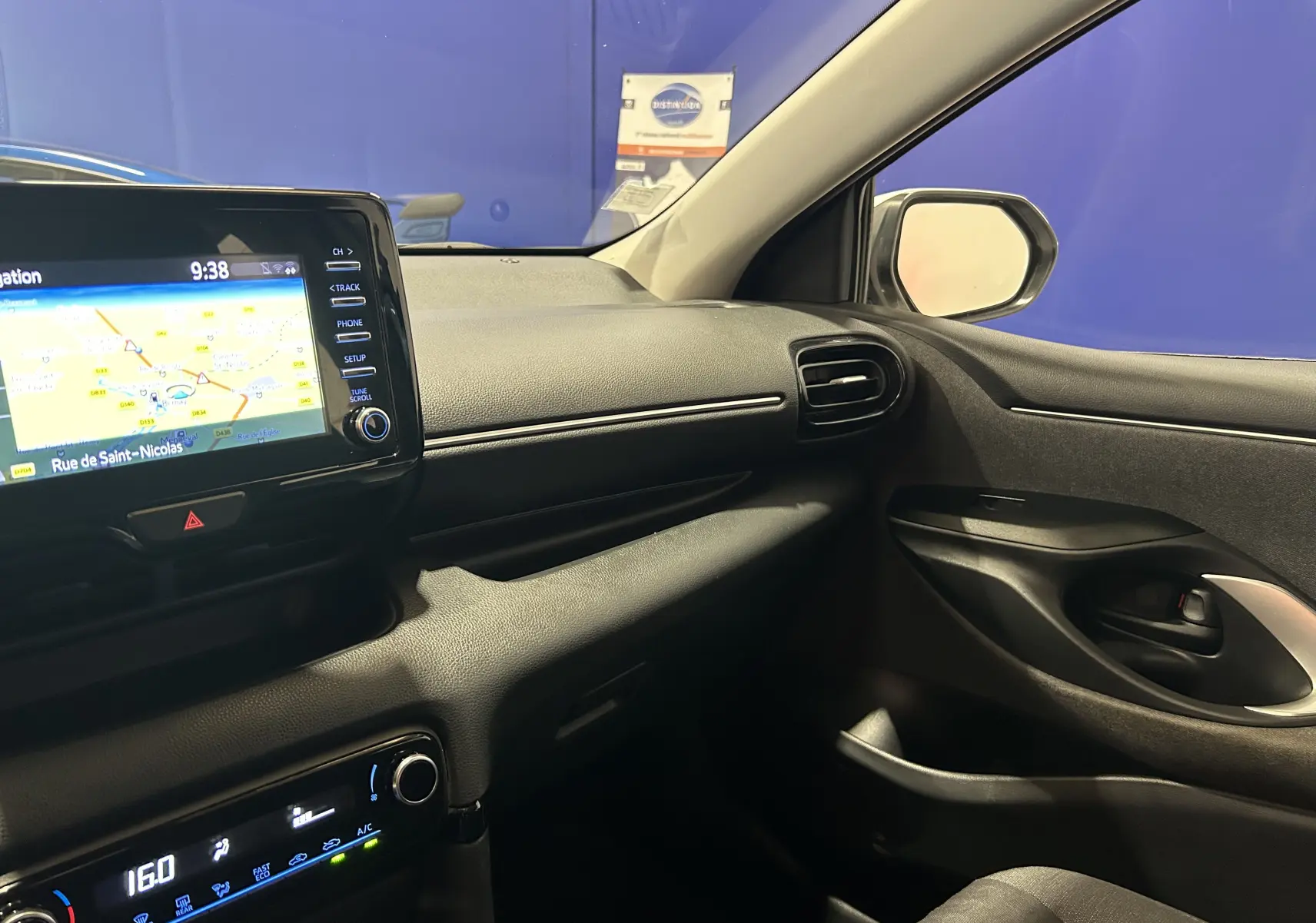 Vue intérieure côté passager de la Toyota Yaris 116h blanche, avec écran GPS et tableau de bord noir.