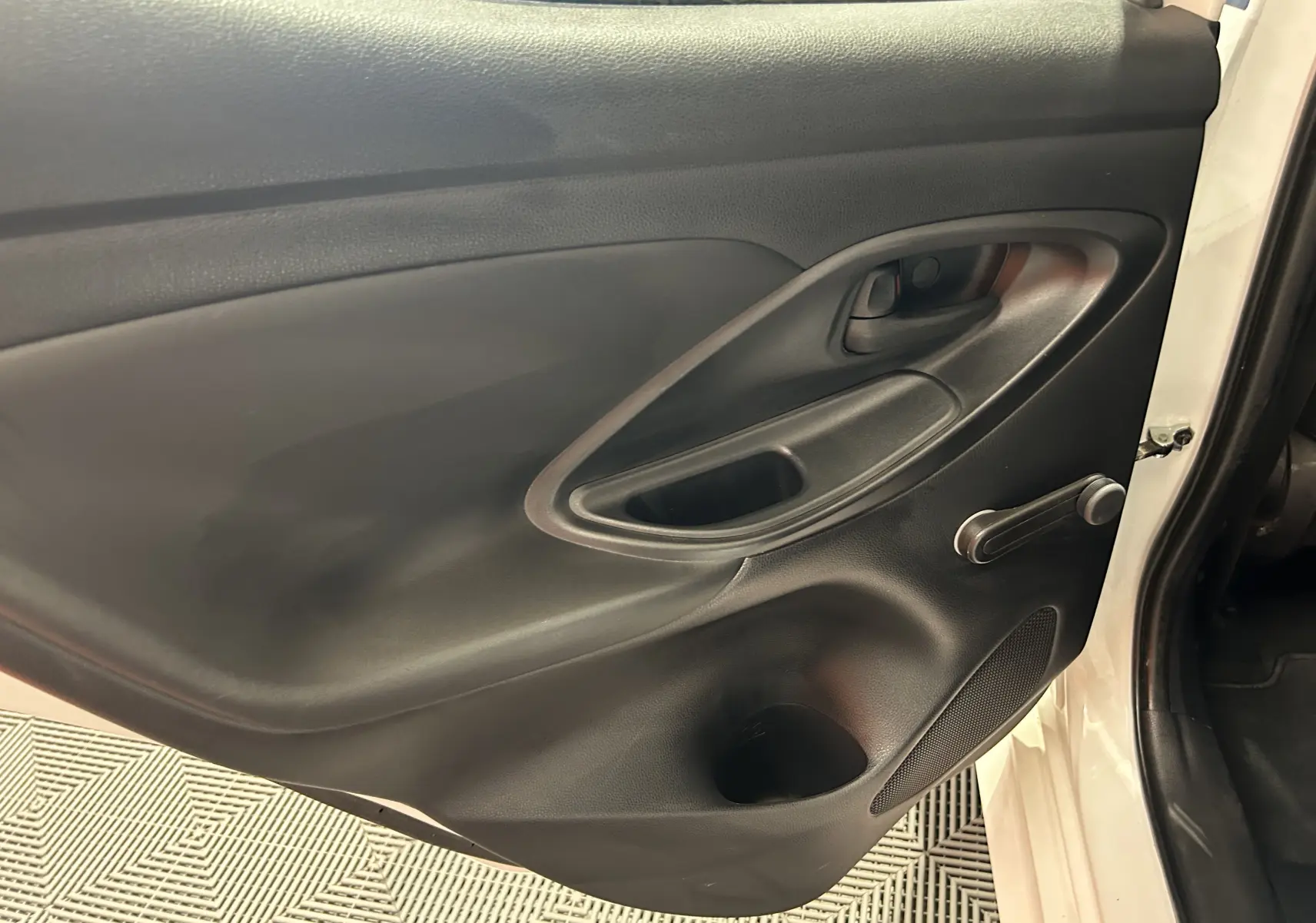 Vue rapprochée de la porte arrière droite noire intérieure d'une Toyota Yaris blanche 2021 avec poignée manuelle.