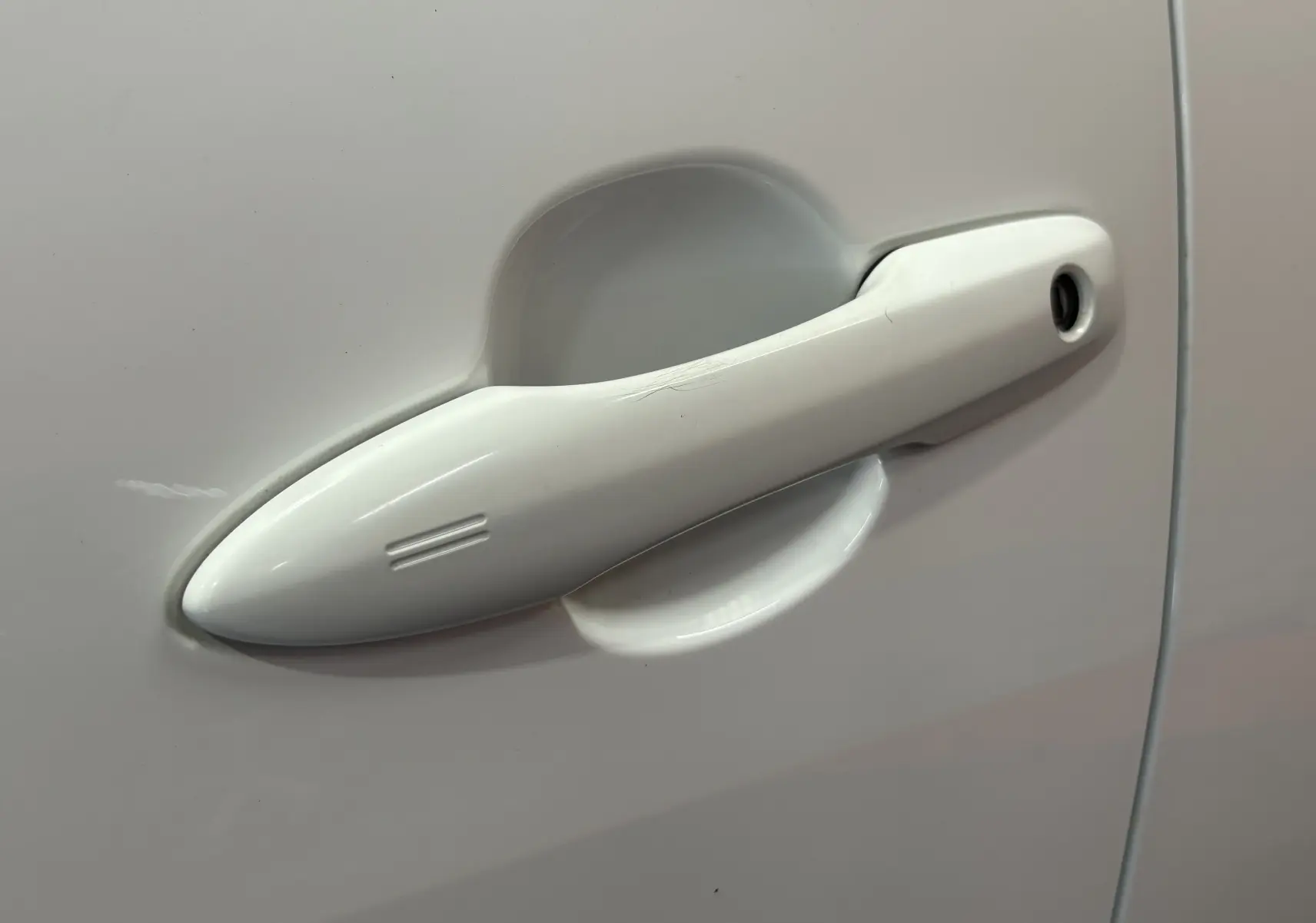 Poignée de porte blanche en gros plan sur la porte côté gauche d'une Toyota Yaris 116h hybride 2021.