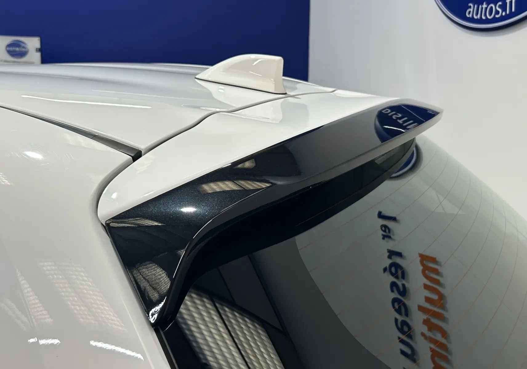 Gros plan sur l'aileron arrière noir et l'antenne requin blanche d'une Toyota Yaris 116h blanche, vue côté arrière droit.