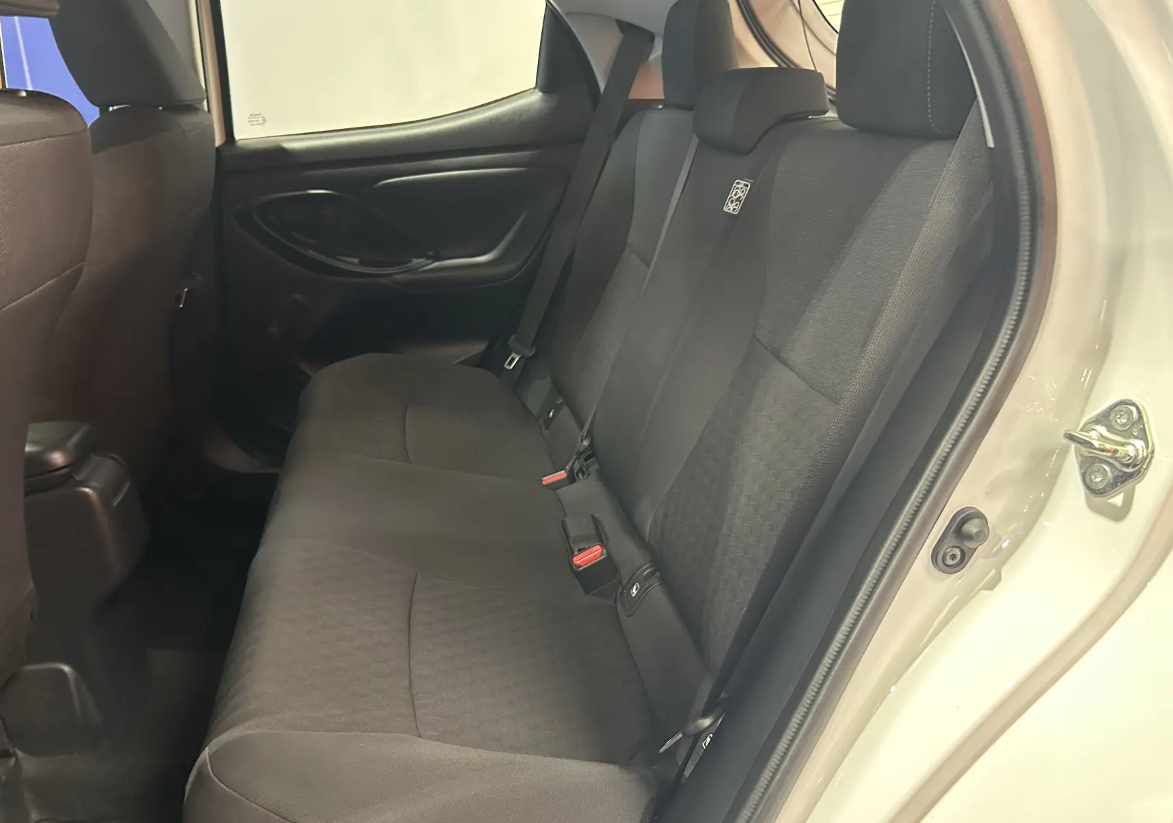 Vue intérieure côté droit des sièges arrière noirs en tissu d'une Toyota Yaris blanche 2021, porte ouverte.