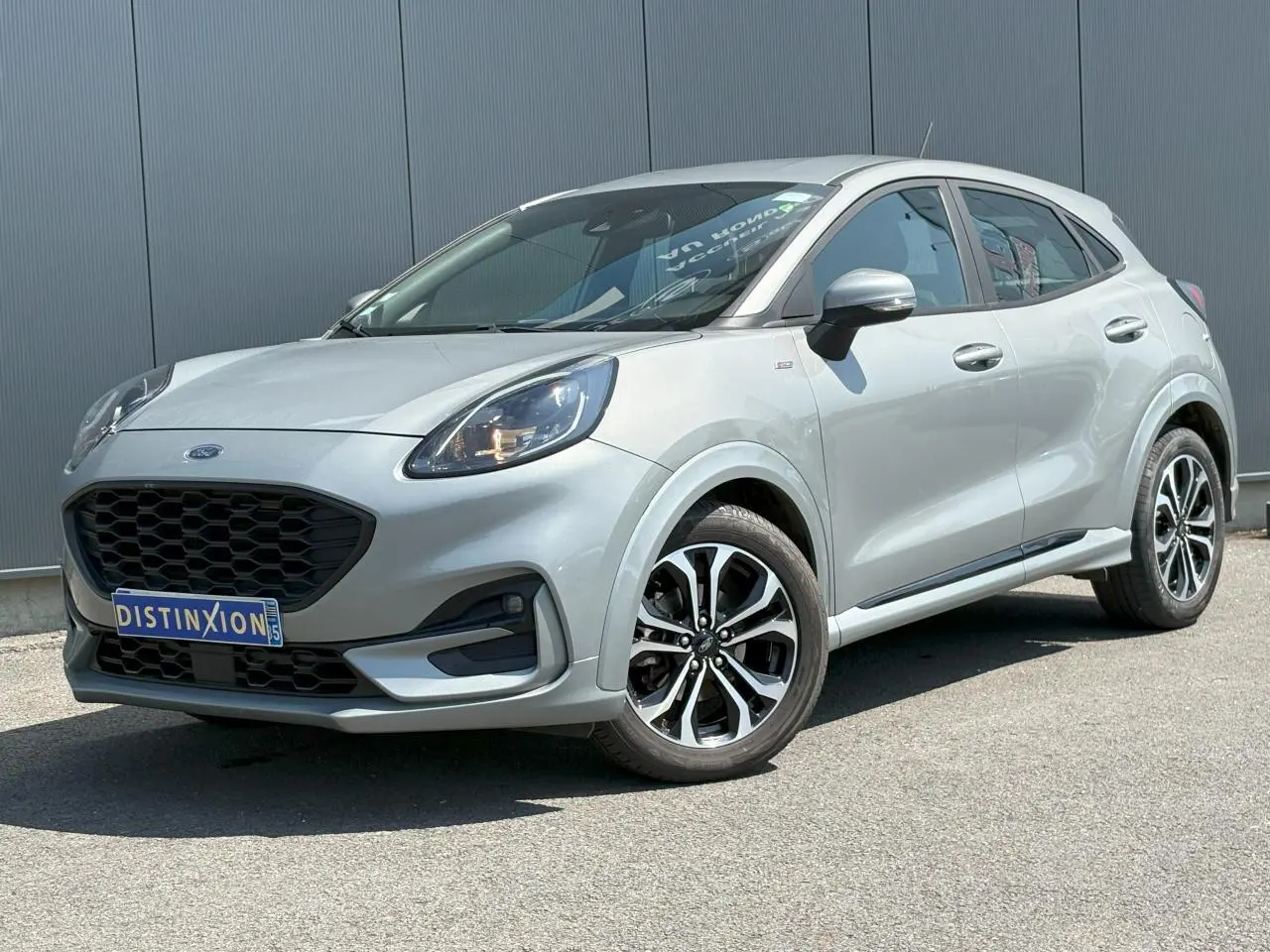 Ford Puma gris Solar en vue 3/4 avant droit, avec jantes alliage noires et calandre noire distinctive.