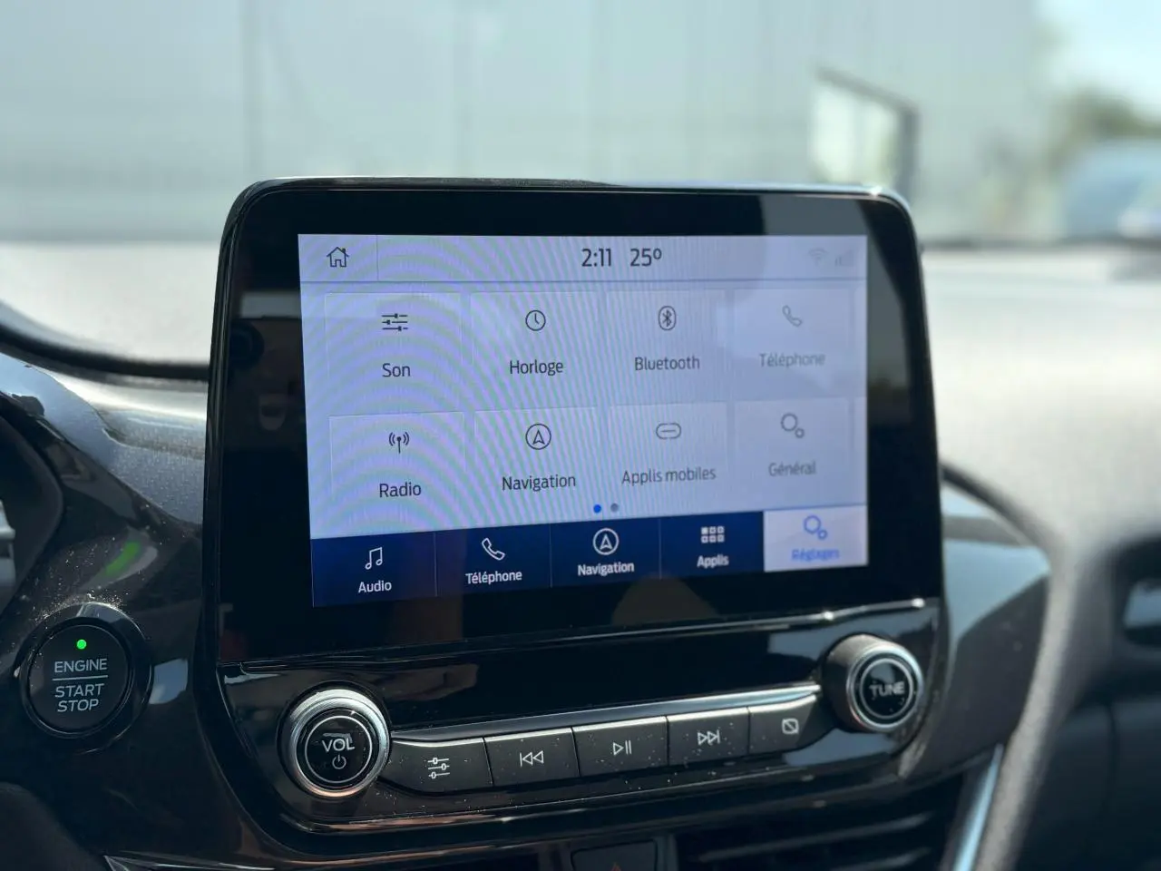 Écran tactile du système Ford SYNC 3 avec commandes vocales et bouton démarrage dans l'habitacle du Ford Puma gris Solar.