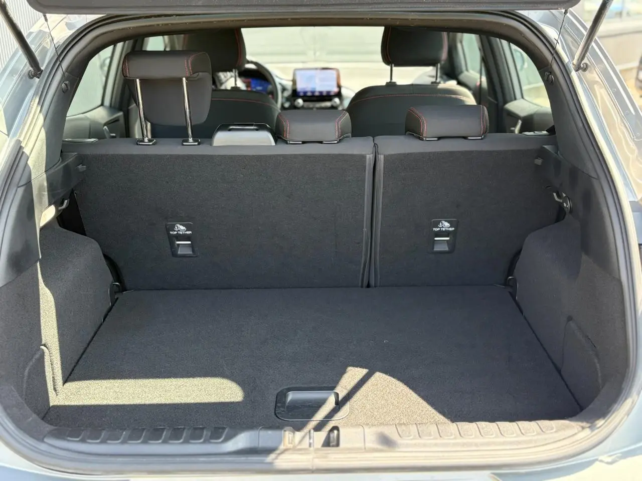 Coffre ouvert du Ford Puma gris Solar, vue arrière montrant la banquette arrière et l'espace de chargement vide.