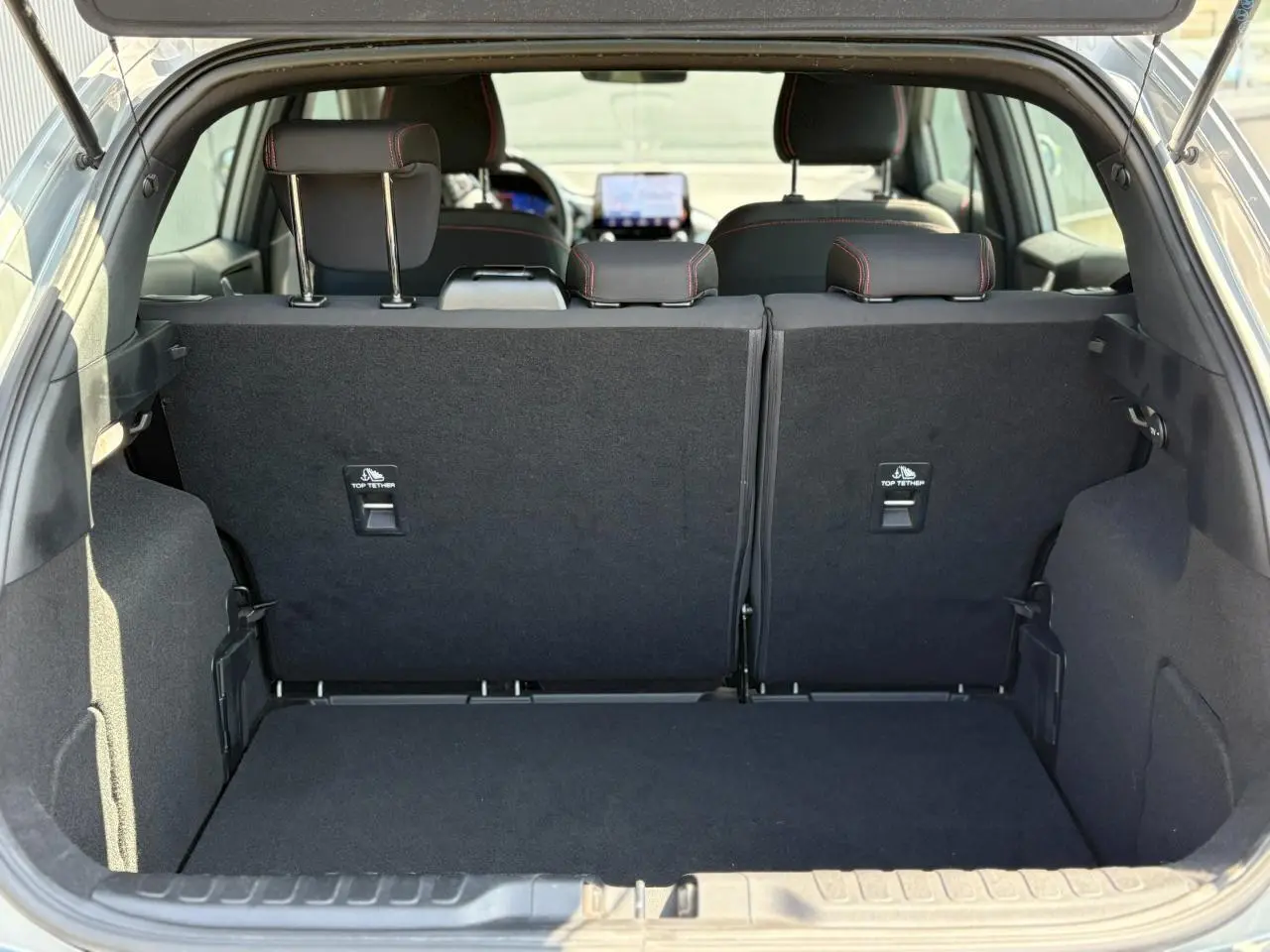 Coffre ouvert vu de l'arrière d'un Ford Puma gris Solar, montrant les sièges arrière et l'espace de chargement noir.