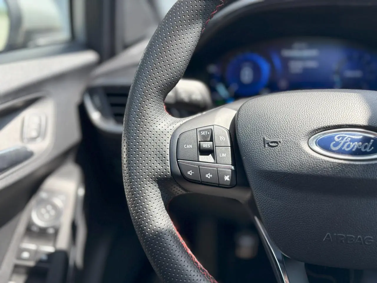 Gros plan sur le volant perforé avec surpiqûres rouges et commandes intégrées du Ford Puma Gris Solar 2020.