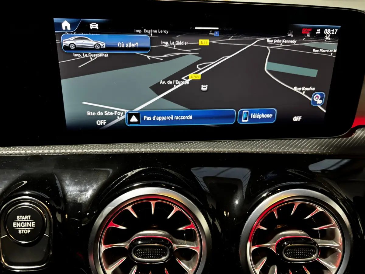 Tableau de bord de Mercedes CLA 250 e AMG Line 2023 avec écran tactile navigation et aérateurs ronds au design métallique rouge.